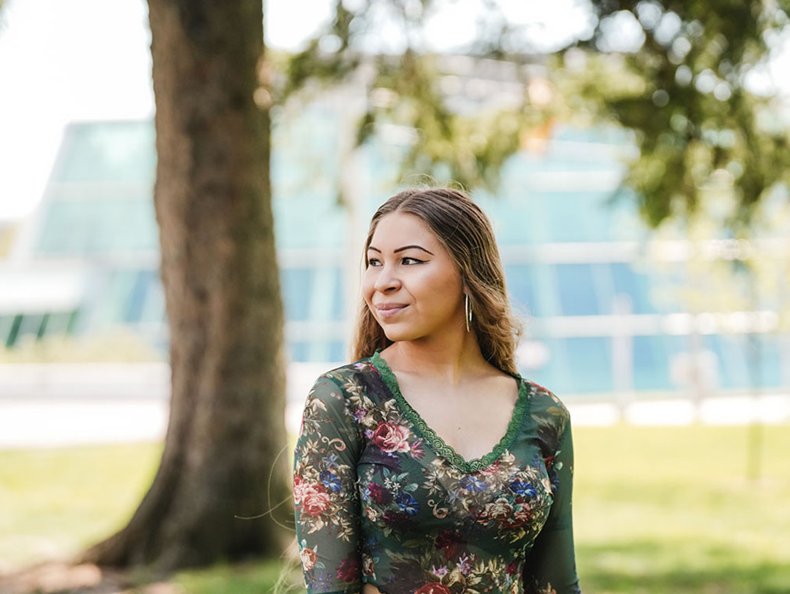 A college student poses for a portrait outside on a college campus